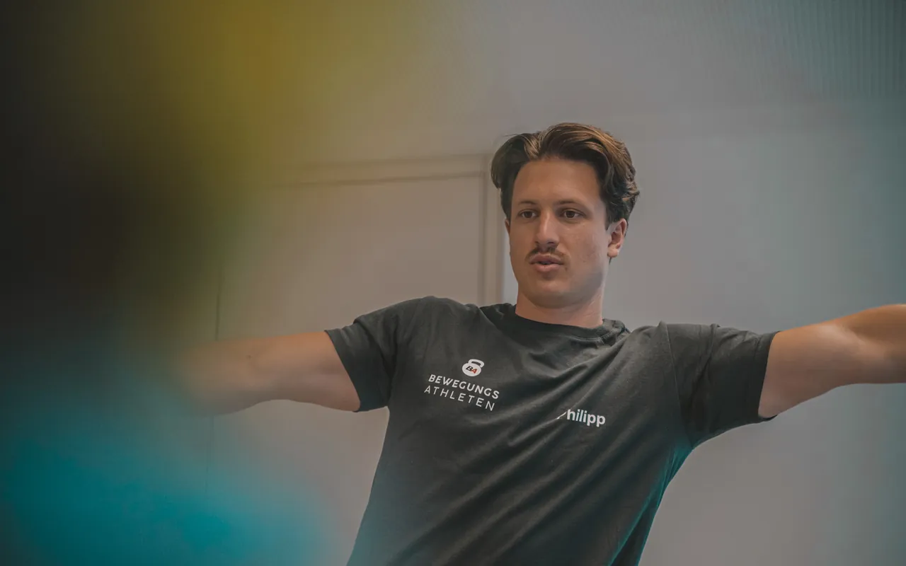 Philipp Schmitt dreht im Trainingsraum den Oberkörper mit ausgebreiteten Armen