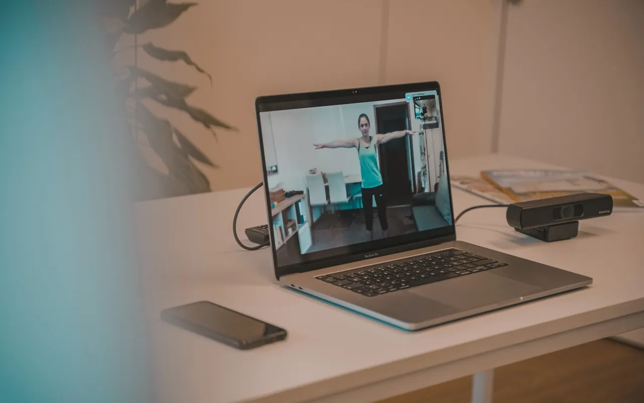 Laptop mit einem Online-Coaching-Termin, auf dem Bildschirm trainiert eine Kundin