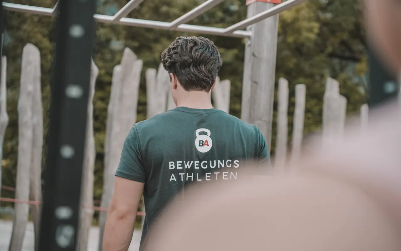 Philipp Schmitt von hinten im Calisthenics-Park, auf dem Shirt das Bewegungsathleten-Logo