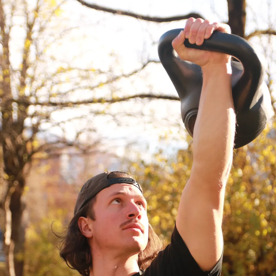 Philipp Schmitt stemmt eine Kettlebell über den Kopf