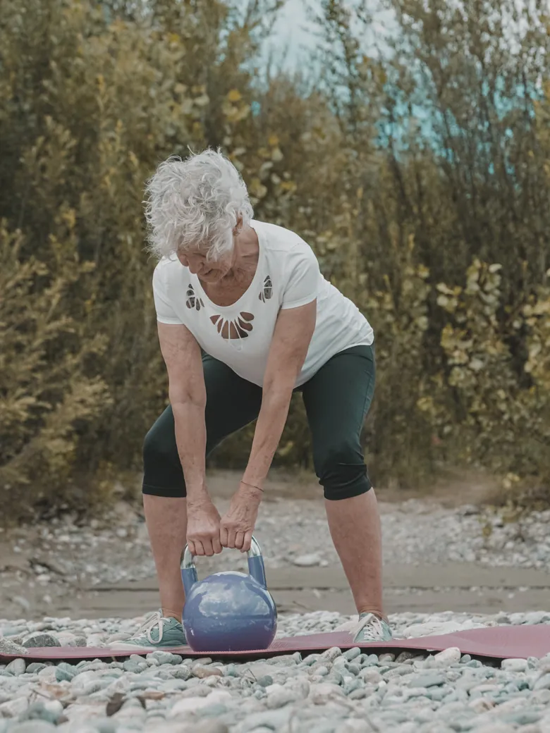 Kundin beim Kettlebell-Kreuzheben am Flussufer