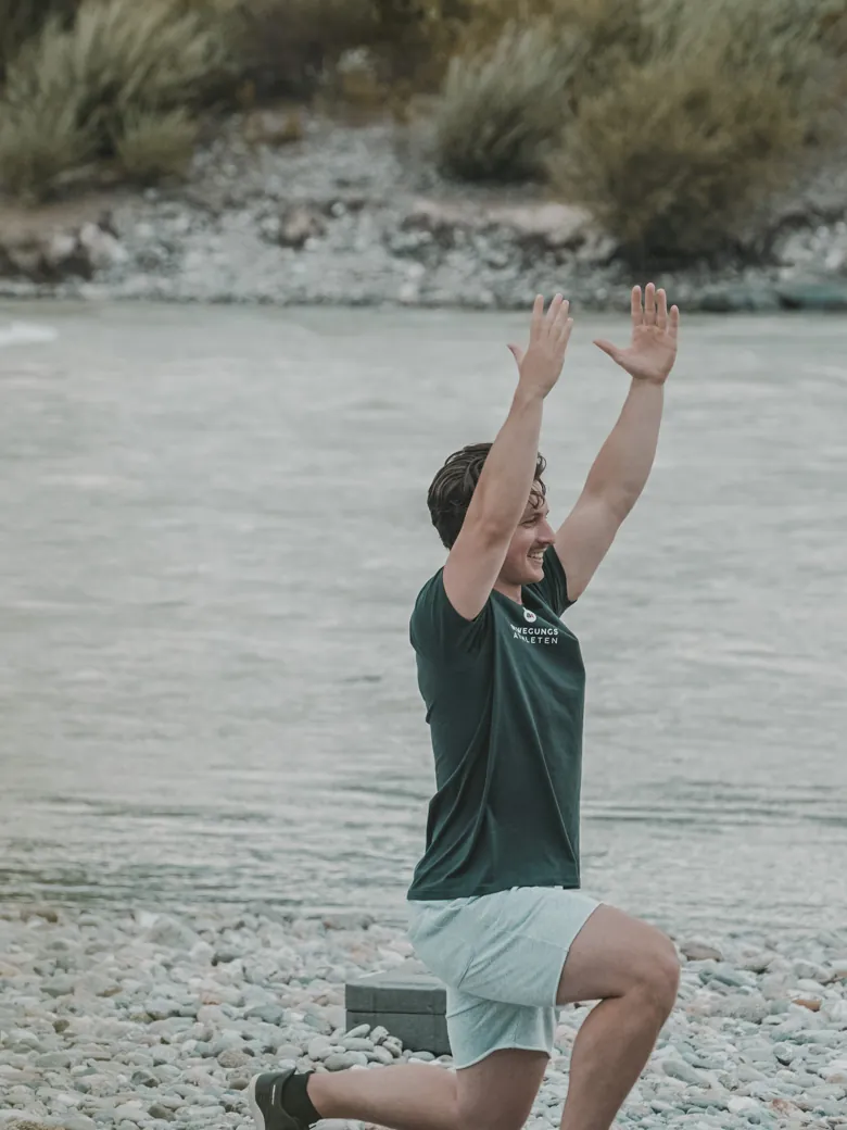 Philipp Schmitt im Ausfallschritt mit gestreckten Armen am Fluss