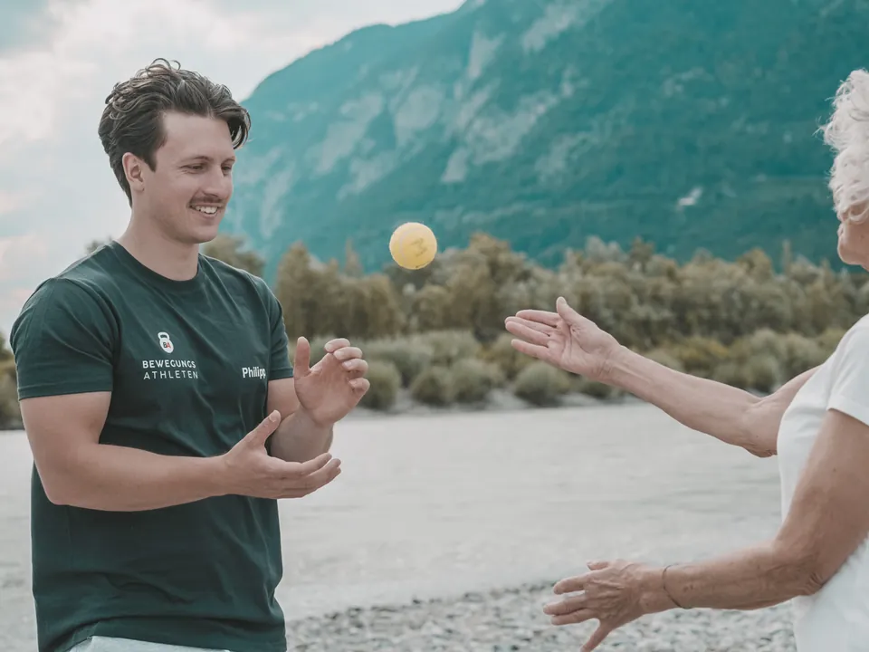 Philipp Schmitt wirft einer Kundin am Fluss lachend einen Ball zu
