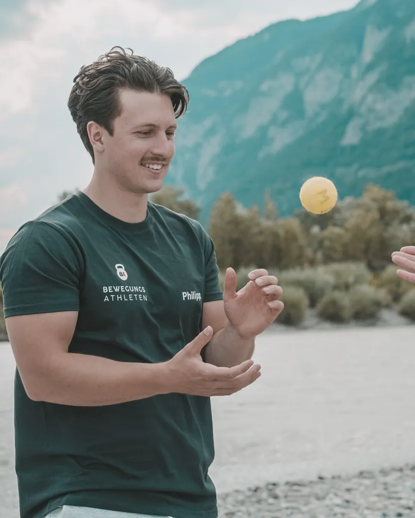 Philipp Schmitt wirft einer Kundin am Flussufer einen Ball zu